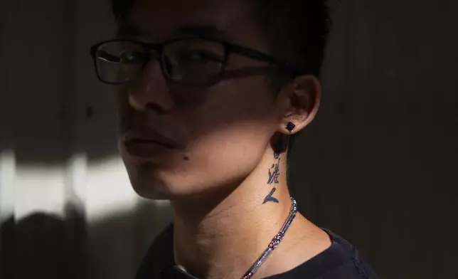 The words Hongkonger can be seen tattooed to the neck of Joker Chan as he poses for photographs after an interview, in Hong Kong, on June 28, 2024. Chan, 30, was sentenced in 2022 for posts containing slogans like “Liberate Hong Kong, revolution of our times,” which were popularly chanted during massive anti-government protests in the city in 2019. Authorities said such slogans could imply separating Hong Kong from China, a red line for Beijing. (AP Photo/Billy H.C. Kwok)