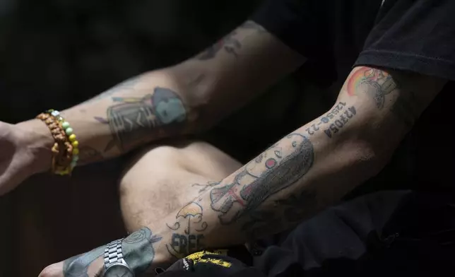 Joker Chan's tattoos including one of his inmate number can be seen after an interview, in Hong Kong, on June 28, 2024. After spending five months in jail for publishing seditious Instagram posts, Joker Chan returned to a harsh reality. Tattoos on his arms, legs and the sides of his neck, some related to anti-government protests, made his job search more difficult. (AP Photo/Billy H.C. Kwok)