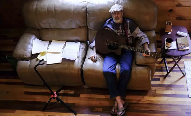 The Rev. Ron Blakely takes a break from rehearsing with sheet music and scripture for his Sunday Gospel Hour at Robert’s Western World honky tonk on Friday, July 26, 2024, at his log cabin home near Watertown, Tenn. (AP Photo/Luis Andres Henao)