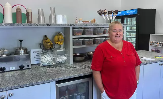 Nancy Thrasher, co-owner of Furlong's Candies &amp; Ice Cream, stands near ice cream and toppings at the store, Wednesday, Aug. 21, 2024, in Norwood, Mass. (AP Photo/Michael Casey)