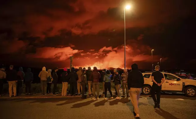 Tourists and visitors try to get a view of the eruption from a distance from the intersection between Reykjanesbraut, Iceland, and the road to Grindavik, Thursday, Aug. 22, 2024. (AP Photo/Marco di Marco)