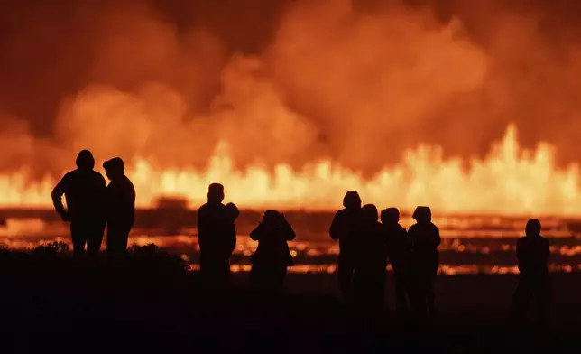 Tourists and visitors try to get a view of the eruption from a distance from the intersection between Reykjanesbraut, Iceland, and the road to Grindavik, Thursday, Aug. 22, 2024. (AP Photo/Marco di Marco)