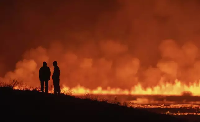 Tourists and visitors try to get a view of the eruption from a distance from the intersection between Reykjanesbraut, Iceland, and the road to Grindavik, Thursday, Aug. 22, 2024. (AP Photo/Marco di Marco)