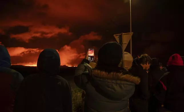 Tourists and visitors try to get a view of the eruption from a distance from the intersection between Reykjanesbraut, Iceland, and the road to Grindavik, Thursday, Aug. 22, 2024. (AP Photo/Marco di Marco)