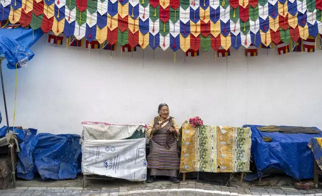 An exiled Tibetan waits with flowers to welcome her spiritual leader the Dalai Lama before he arrives in Dharamshala, India, Wednesday, Aug. 28, 2024. (AP Photo/Ashwini Bhatia)