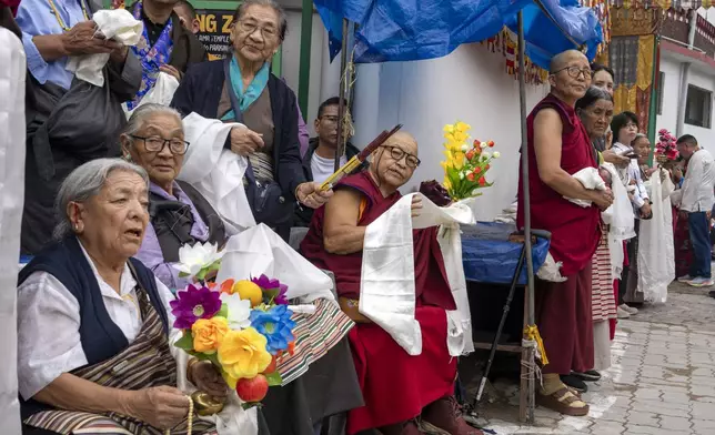 Exiled Tibetans wait with ceremonial scarves and flowers to welcome their spiritual leader the Dalai Lama before he arrived in Dharamshala, India, Wednesday, Aug. 28, 2024. (AP Photo/Ashwini Bhatia)