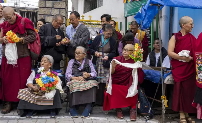 Exiled Tibetans wait with ceremonial scarves and flowers to welcome their spiritual leader the Dalai Lama before he arrives in Dharamshala, India, Wednesday, Aug. 28, 2024. (AP Photo/Ashwini Bhatia)