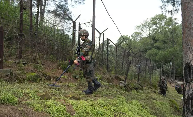 An Indian army soldier sanitizes a patch during a drill along the highly militarized Line of Control that divides Kashmir region between India and Pakistan, in Nowshera sector about 127 kilometers (79 miles) from Jammu, India, Monday, Aug.12, 2024. (AP Photo/Channi Anand)