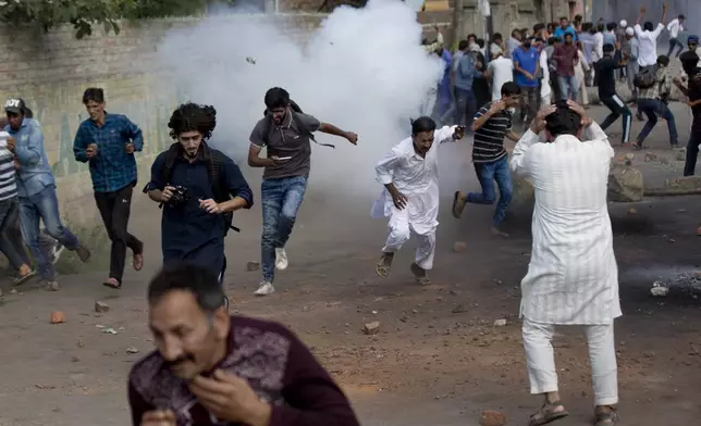 Kashmiris run for cover as a tear gas shell explodes near them during a protest in Srinagar Indian controlled Kashmir, Friday, Aug. 23, 2019. (AP Photo/ Dar Yasin, File)