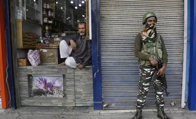 An Indian paramilitary soldier stands guard as a Kashmiri shopkeeper waits for customers in Srinagar, Indian controlled Kashmir, Monday, July 1, 2019. (AP Photo/Mukhtar Khan, File)