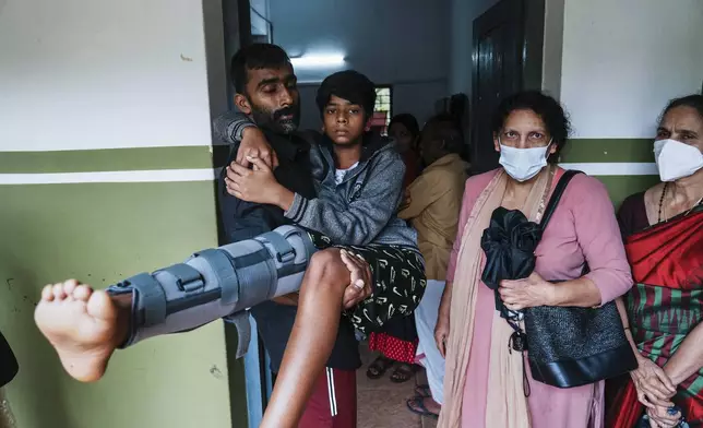 Prajesh Tindu carries his brother Alban Tindu at a government-run relief camp for survivors set up at a school building third day after landslides set off by torrential rains in Wayanad district, Kerala state, India, Thursday, Aug. 1, 2024. (AP Photo/Rafiq Maqbool)