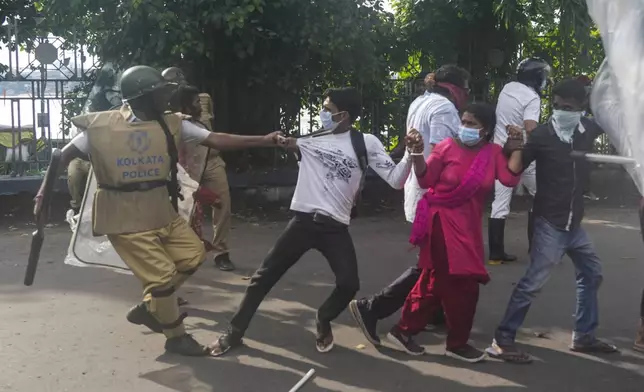 A policeman grabs protesters against the rape and murder of a resident doctor at a government hospital earlier this month, in Kolkata, India, Tuesday, Aug. 27, 2024. (AP Photo/Bikas Das)