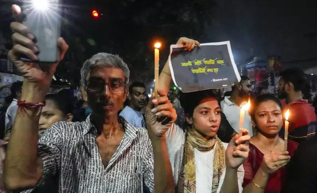 A family hold candle light as they join protesters in a midnight rally protesting against the murder of a 31 year old post-graduate trainee demanding proper investigation in Kolkata, India, Wednesday, Aug. 14, 2024. (AP Photo/Bikas Das)