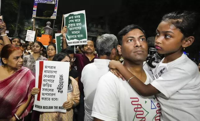 A father carries his girl child as they join other protesters in a midnight rally protesting against the murder of a 31 year old post-graduate trainee demanding proper investigation in Kolkata, India, Wednesday, Aug. 14, 2024. (AP Photo/Bikas Das)