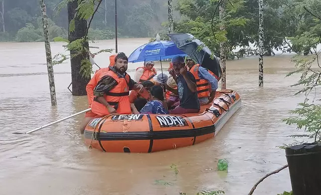 In this photo made available by the National Disaster Response Force (NDRF), NDRF personnel transport people to safety through a flooded area following incessant rains on the outskirts of Agartala, north eastern Tripura state, India, Thursday, Aug. 22, 2024.(National Disaster Response Force via AP)