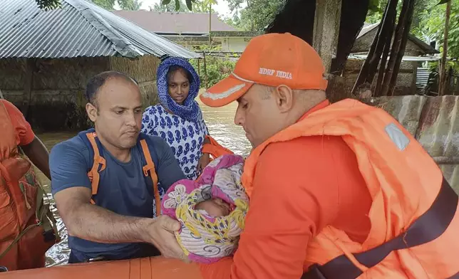 In this photo made available by the National Disaster Response Force (NDRF), an NDRF person carries an infant to safety in a flood-affected area on the outskirts of Agartala, north eastern Tripura state, India, Thursday, Aug. 22, 2024. (National Disaster Response Force via AP)