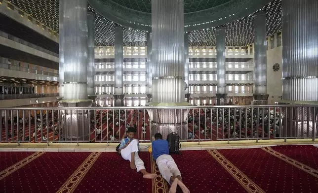 Indonesian students wait for the start of Friday prayers at Istiqlal Mosque in Jakarta, Indonesia, Friday, Aug. 9, 2024. (AP Photo/Tatan Syuflana)