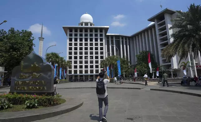 A man uses his mobile phone to take photos outside Istiqlal Mosque in Jakarta, Indonesia, Friday, Aug. 9, 2024, where Pope Francis is scheduled to hold an interfaith meeting on Sept. 5. (AP Photo/Tatan Syuflana)