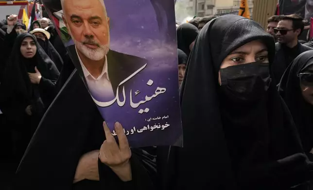 An Iranian woman holds up a poster of Hamas leader Ismail Haniyeh with Arabic writing: "Congratulations Haniyeh!" during his funeral ceremony and of his bodyguard, after they were killed in an assassination blamed on Israel on Wednesday, at Enqelab-e-Eslami (Islamic Revolution) Sq. in Tehran, Iran, Thursday, Aug. 1, 2024. (AP Photo/Vahid Salemi)