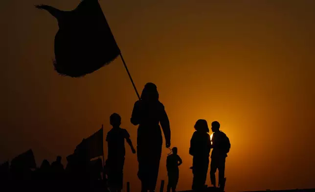 The sun sets as Shiite pilgrims march on their way to Karbala for Arbaeen in Babil, Iraq, Monday, Aug. 19, 2024. (AP Photo/Hadi Mizban)