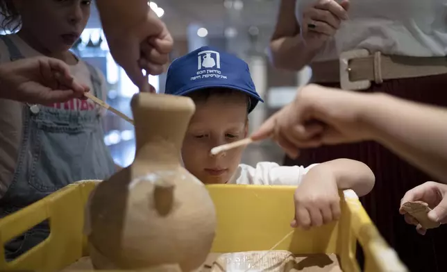 Ariel Heller, 4, helps to glue a broken clay jar during a special tour with his family after he accidentally broke another jar at the Reuben and Edith Hecht Museum in Haifa, Israel, Friday, Aug. 30, 2024. The boy who accidentally broke a rare 3,500-year-old jar in an Israeli museum has been forgiven and invited back, as curators hope to turn the disaster into a teachable moment. (AP Photo/Maya Alleruzzo)