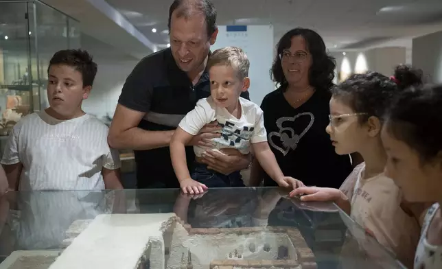 Ariel Heller, 4, center, and his parents Anna, right, and Alex, center left, take part in a special tour after the child accidentally broke an ancient jar at the Reuben and Edith Hecht Museum in Haifa, Israel, Friday, Aug. 30, 2024. The boy who accidentally broke a rare 3,500-year-old jar in an Israeli museum has been forgiven and invited back, as curators hope to turn the disaster into a teachable moment. (AP Photo/Maya Alleruzzo)