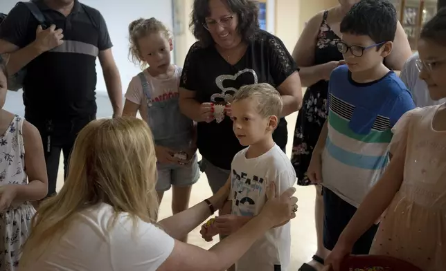 Ariel Heller, 4, center, is welcomed by Dr. Inbal Rivlin for a special tour after the child accidentally broke an ancient jar at the Reuben and Edith Hecht Museum in Haifa, Israel, Friday, Aug. 30, 2024. The boy who accidentally broke a rare 3,500-year-old jar in an Israeli museum has been forgiven and invited back, as curators hope to turn the disaster into a teachable moment. (AP Photo/Maya Alleruzzo)