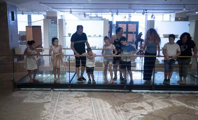 Ariel Heller, 4, center left, and his father Alex, third left, take part in a special tour with their family and friends after the child accidentally broke an ancient jar at the Reuben and Edith Hecht Museum in Haifa, Israel, Friday, Aug. 30, 2024. The boy who accidentally broke a rare 3,500-year-old jar in an Israeli museum has been forgiven and invited back, as curators hope to turn the disaster into a teachable moment. (AP Photo/Maya Alleruzzo)