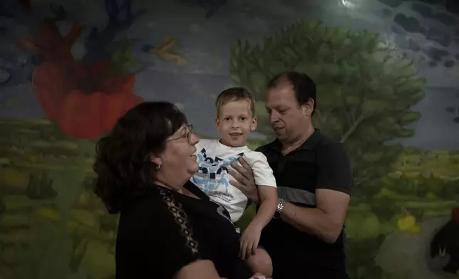 Ariel Heller, 4, poses for a portrait with his parents Anna, left, and Alex, right, after the family was invited for a special tour after he accidentally broke an ancient jar at the Reuben and Edith Hecht Museum in Haifa, Israel, Friday, Aug. 30, 2024. The boy who accidentally broke a rare 3,500-year-old jar in an Israeli museum has been forgiven and invited back, as curators hope to turn the disaster into a teachable moment. (AP Photo/Maya Alleruzzo)