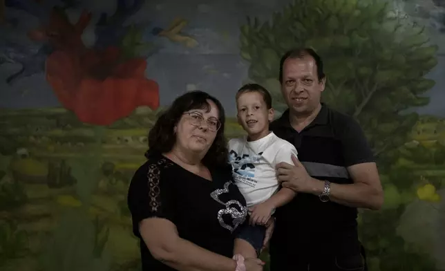 Ariel Heller, 4, poses for a portrait with his parents Anna, left, and Alex, right, as the family was invited for a special tour after he accidentally broke an ancient jar at the Reuben and Edith Hecht Museum in Haifa, Israel, Friday, Aug. 30, 2024. The boy who accidentally broke a rare 3,500-year-old jar in an Israeli museum has been forgiven and invited back, as curators hope to turn the disaster into a teachable moment. (AP Photo/Maya Alleruzzo)