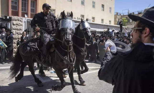 Israeli police officers scuffle with ultra-Orthodox Jewish men during a protest against a potential new draft law which could end their exemptions from military service in Jerusalem, Wednesday, Aug. 21, 2024. (AP Photo/Ohad Zwigenberg)