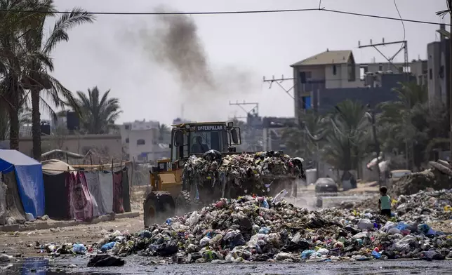 A bulldozer cleans up plastic and other waste materials at a street in Deir al-Balah, central Gaza Strip, Tuesday, Aug. 27, 2024. (AP Photo/Abdel Kareem Hana)