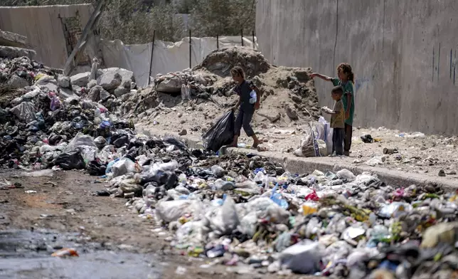 Displaced kids sort through trash at a street in Deir al-Balah, central Gaza Strip, Tuesday, Aug. 27, 2024. (AP Photo/Abdel Kareem Hana)