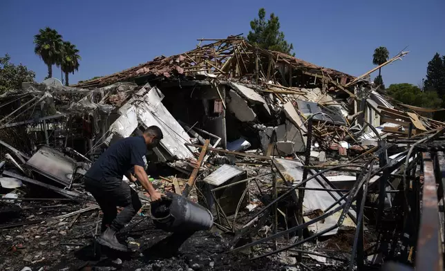 A man works next to a destroyed home after rockets struck in Katzrin, in the Israeli-annexed Golan Heights, Wednesday, Aug. 21, 2024. Lebanon's Hezbollah has launched more than 50 rockets, hitting a number of private homes in the area.(AP Photo/Ariel Schalit)