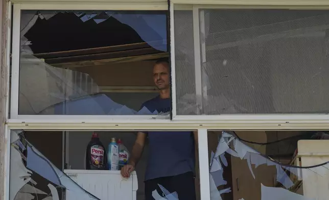 A man looks at a damaged window of a house following an attack from Lebanon, in Acre, north Israel, Sunday, Aug. 25, 2024. (AP Photo/Ariel Schalit)