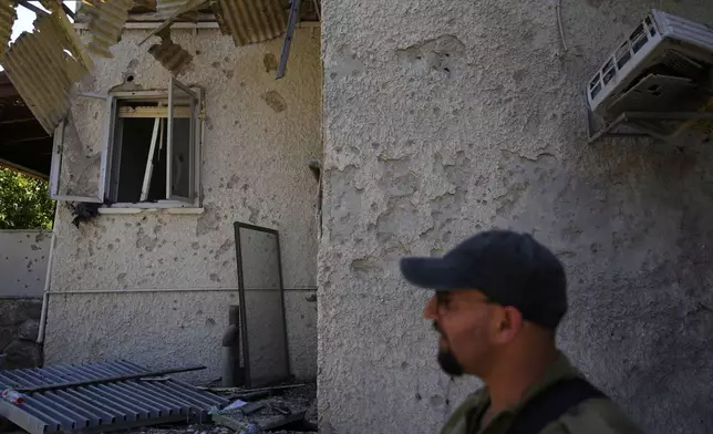 An Israeli soldier examines a home after rockets struck in Katzrin, in the the Israeli-annexed Golan Heights, Wednesday, Aug. 21, 2024. Lebanon's Hezbollah has launched more than 50 rockets, hitting a number of private homes in the area.(AP Photo/Ariel Schalit)