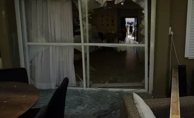 A woman stands on the doorway of a damaged house following an attack from Lebanon, in Acre, north Israel, Sunday, Aug. 25, 2024. (AP Photo/Ariel Schalit)