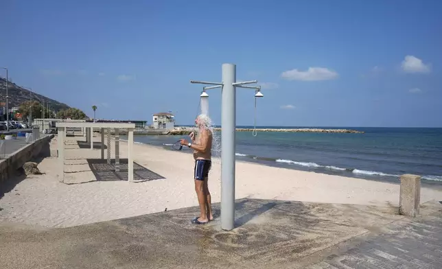 A man takes a shower on the edge of beach after local authorities restricted the public access to the beaches of Haifa, following the attacks from Lebanon, in northern Israel, Sunday, Aug. 25, 2024. (AP Photo/Ariel Schalit)