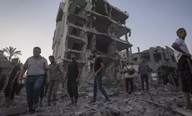 Palestinians stand in rubble after an Israeli airstrike in Deir al Balah, Gaza Strip, Tuesday, Aug. 6, 2024. (AP Photo/Abdel Kareem Hana)