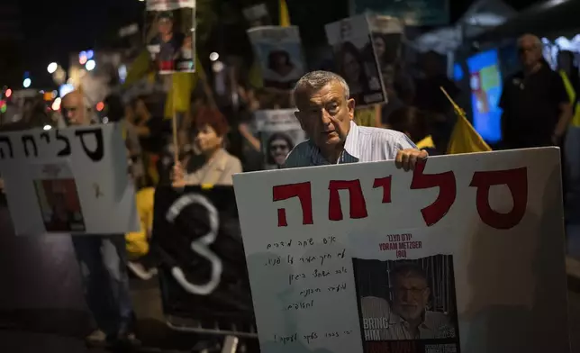 A demonstrator holds a banner with a portrait of the slain hostage Yoram Metzger, who was taken by Hamas militants to the Gaza Strip in Oct. 7 attack, during a protest, in Jerusalem, Tuesday, Aug. 20, 2024. People gather to honor the memories of six men whose bodies were returned and to call for a deal to release the remaining captives. (AP Photo/Leo Correa)