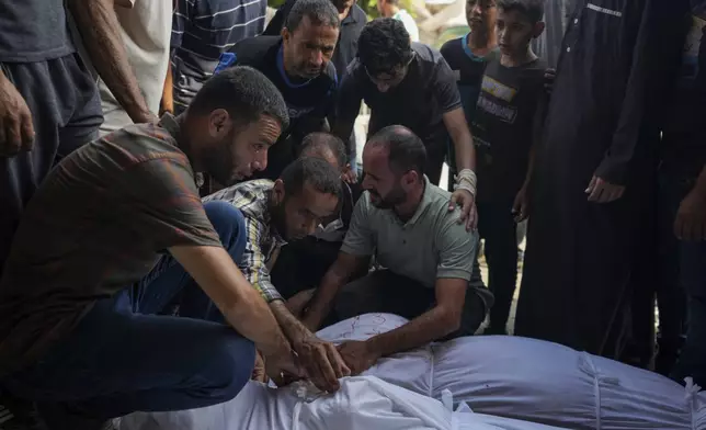 Palestinians mourn relatives killed in the Israeli bombardment of the Gaza Strip, at a hospital in Deir al-Balah, Tuesday, Aug. 27, 2024. (AP Photo/Abdel Kareem Hana)