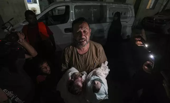 Osama al-Taweel holds the bodies of his grandchildren who were killed during an Israel airstrike in the Gaza Strip, as he arrives at the hospital morgue in Deir al Balah, Thursday, Aug. 29, 2024. (AP Photo/Abdel Kareem Hana)