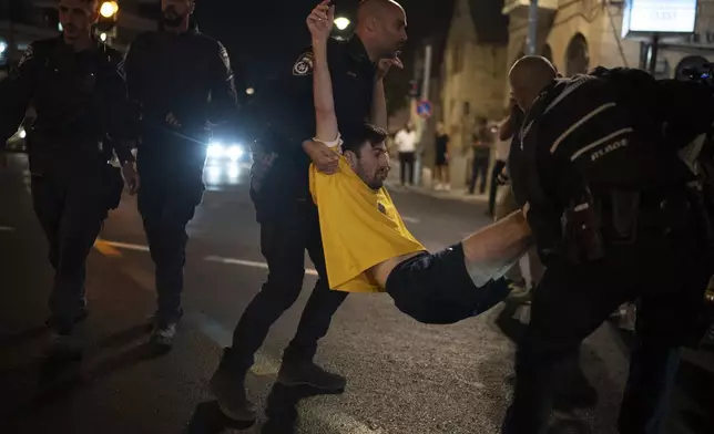 Israeli police officers move a demonstrator blocking a street during a protest, in Jerusalem, Tuesday, Aug. 20, 2024. People gather to honor the memories of six men whose bodies were returned and to call for a deal to release the remaining captives. (AP Photo/Leo Correa)