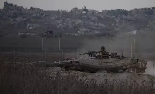 Israeli soldiers move on the top of a tank near the Israeli-Gaza border, as seen from southern Israel, Wednesday, Aug. 21, 2024. (AP Photo/Leo Correa)