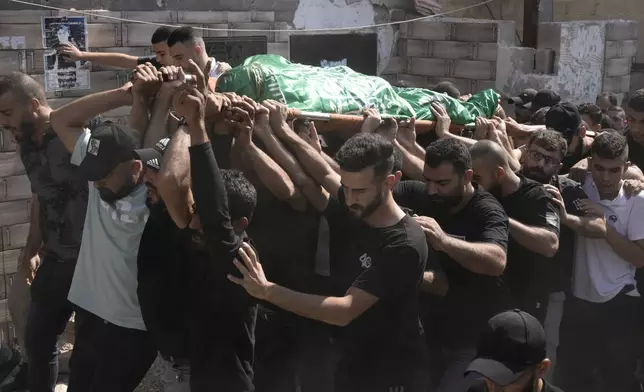 Mourners march during a funeral with the body of Palestinian Raafat Dawasa from the town of Silat Al-Harithiya, draped in the Hamas flag in the Jenin refugee camp, in the West Bank city of Jenin, Sunday, Aug. 18, 2024. Israel's military said Saturday it struck a "terrorist cell" in Jenin. The Palestinian health ministry there said two bodies were taken to a government hospital; Hamas claimed the two men as commanders in its military wing. (AP Photo/Majdi Mohammed)