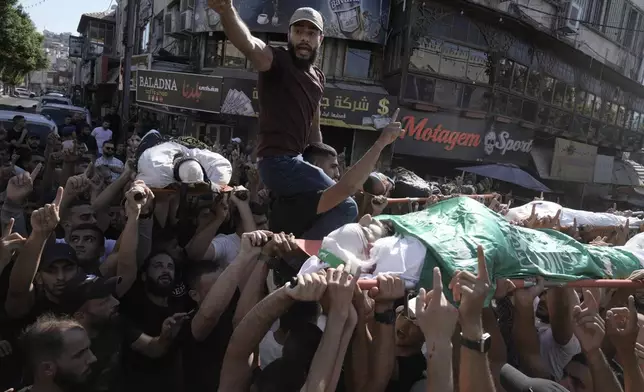 Mourners carry the bodies of five Palestinians during their funeral, draped in flags of the Hamas and Islamic Jihad militant groups, killed by an Israeli strike on a vehicle in the West Bank city of Jenin, Tuesday, Aug. 6, 2024. (AP Photo/Majdi Mohammed)