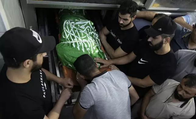 Mourners bid farewell to Ahmed Abu Arra from the town of Aqaba, draped in the Hamas flag, before the funeral for two Palestinians killed in an Israeli strike in the Jenin refugee camp, in the West Bank city of Jenin, Sunday, Aug. 18, 2024. Israel's military said Saturday it struck a "terrorist cell" in Jenin. The Palestinian health ministry there said two bodies were taken to a government hospital; Hamas claimed the two men as commanders in its military wing. (AP Photo/Majdi Mohammed)