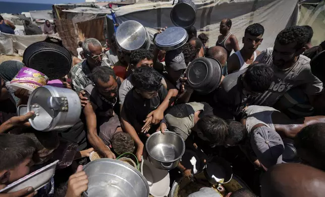 Displaced Palestinians at a food distribution center in Deir al Balah, central Gaza Strip, Friday, Aug. 23, 2024. (AP Photo/Abdel Kareem Hana)