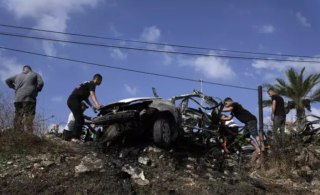 Palestinians gather around a car destroyed in a drone strike Zeita village, north of the West Bank city of Tulkarem, Saturday, Aug. 3, 2024. The Israeli military says it struck five suspected terrorists in a vehicle on their way to carry out an attack. (AP Photo/Majdi Mohammed)