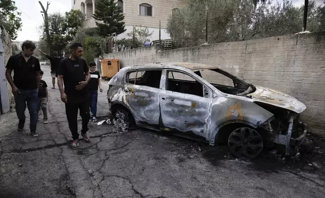 Palestinians check a damaged car following a military operation in the West Bank town of Zababdeh, south of Jenin, Friday, Aug. 30, 2024. (AP Photo/Majdi Mohammed)